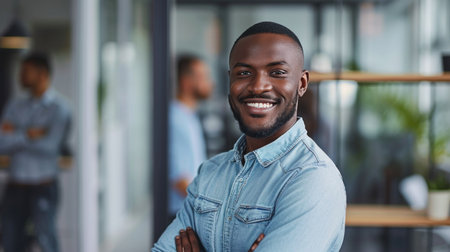 Portrait of a handsome smiling black businessman boss standing in his modern business company office.の素材