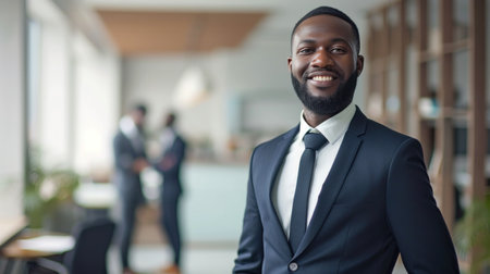 Portrait of a handsome smiling black businessman boss standing in his modern business company office.の素材