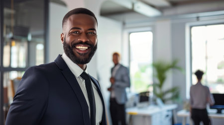 Portrait of a handsome smiling black businessman boss standing in his modern business company office.の素材