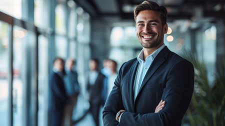 Portrait of a handsome smiling businessman boss standing in his modern business company office.の素材