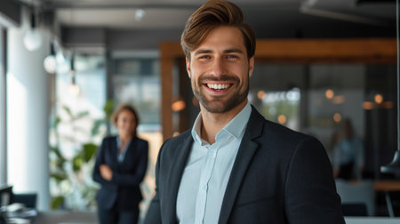 Portrait of a handsome smiling businessman boss standing in his modern business company office.の素材
