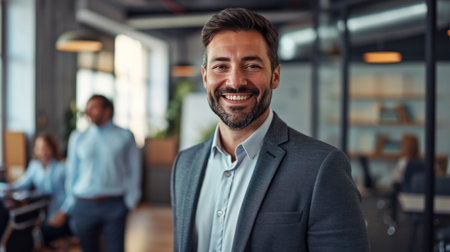 Portrait of a handsome smiling businessman boss standing in his modern business company office.の素材