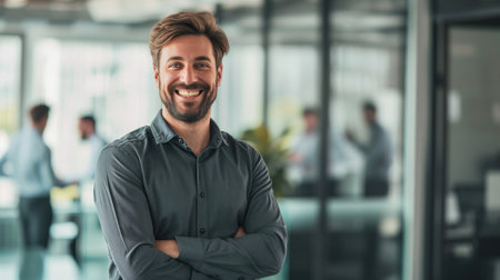 Portrait of a handsome smiling businessman boss standing in his modern business company office.の素材