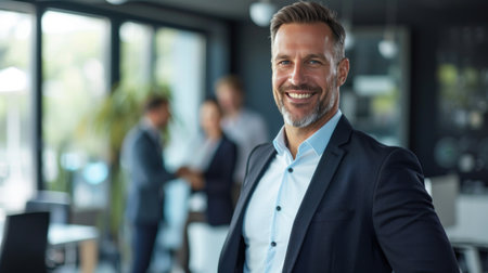 Portrait of a handsome smiling businessman boss standing in his modern business company office.の素材