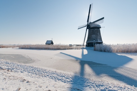 dutch windmill in  snow in clear blue skyの写真素材