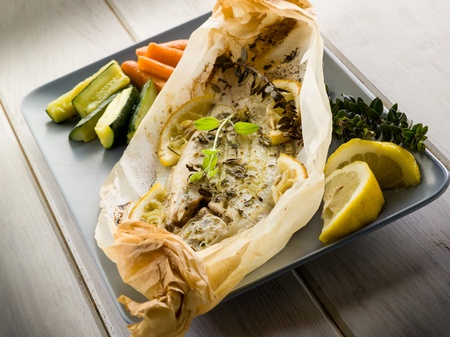sole fish cocked in a wrapper with herbs and sliced lemonの写真素材