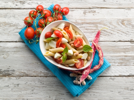 cold pasta salad with slice tomatoes mozzarella and beansの写真素材