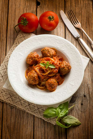 spaghetti with meatballs and tomato sauce over wooden backgroundの写真素材
