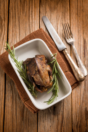roasted pigeon with herbs over wood backgroundの写真素材