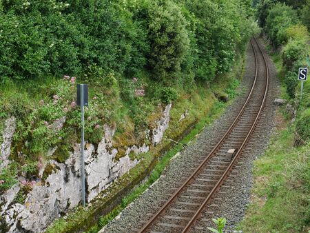 rusty railway cuts the hill surrounded by green natureの写真素材