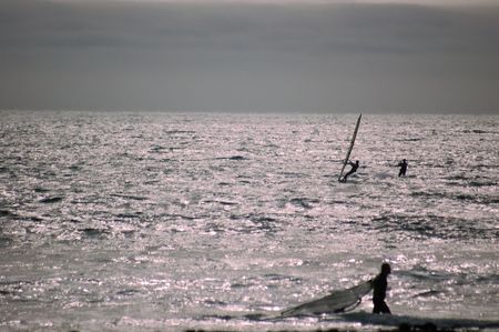 A parasurfer and a couple of windsurfers coming to shore nad calling it quits for the day, near Santa Cruz, California.の写真素材