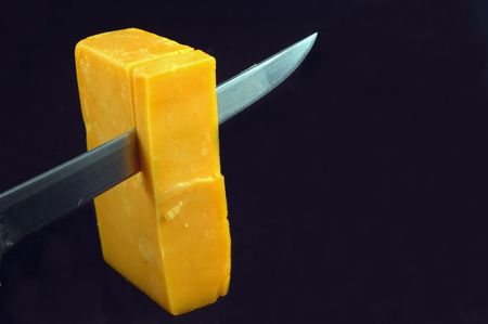 Knife slicing through extra sharp cheddar cheeseの写真素材