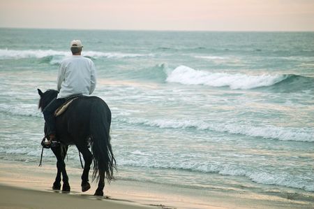 riding into the sunset on the beachの写真素材