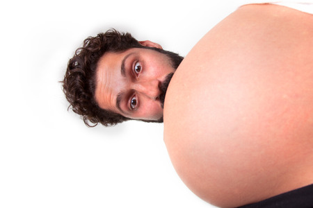 Surprised man head peek out from behind the pregnant stomachの写真素材