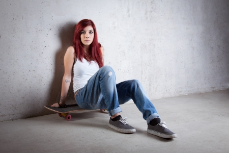Woman with skateboard portrait against concrete wall.の写真素材