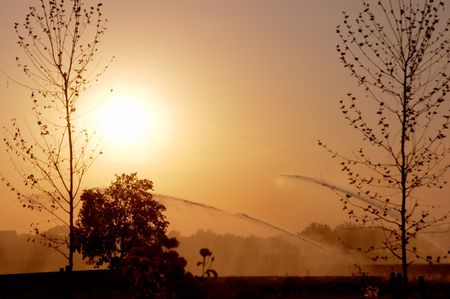 Backlight of red summer sunset and irrigation pumps in Gossolengo countryside, Piacenza, Italyの写真素材