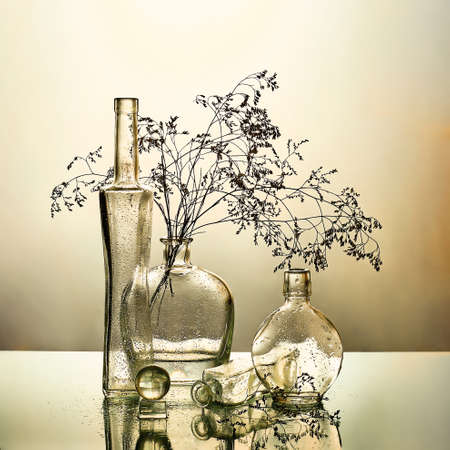 still life with glass bottles and branchesの写真素材