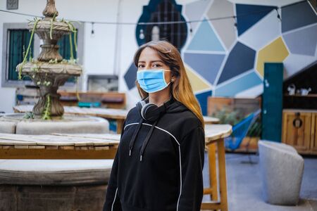 Latin girl wearing face mask for social distancing in new normal situation protecting and preventing the infection of covid-19, mexican woman in Mexico cityの写真素材