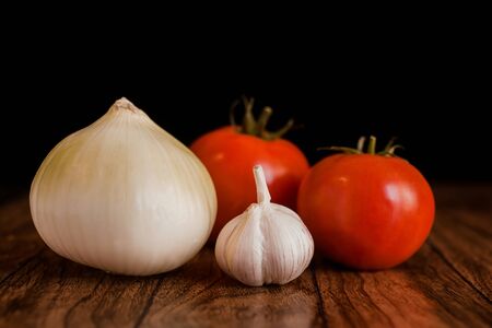 tomato, garlic, onion and rosemary on a wooden black backgroundの写真素材