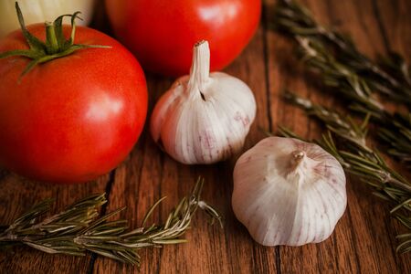 tomato, garlic, onion and rosemary on a wooden black backgroundの写真素材