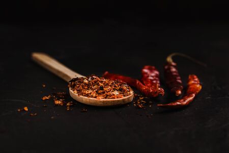 Dried red chili peppers and chili powder spice on black background