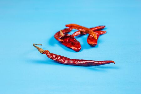 Dried red chili peppers and chili powder spice on blue background