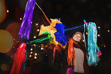 Mexican Woman Holding a colorful PiÃ±ata celebrating Christmas in a traditional Posada in Mexico Cityの写真素材