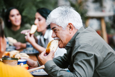 mexican senior man eating rosca de reyes with traditional mexican chocolate cup in Mexicoの写真素材