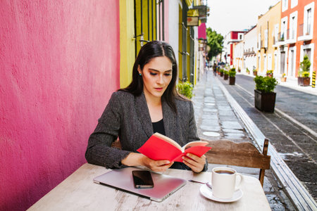 mexican woman reading a book in a coffee shop terrace in a colonial city of latin americaの写真素材