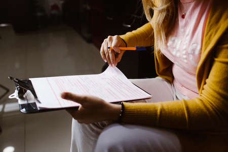Latin woman hands writing and signing a document or a questionnaire in South America