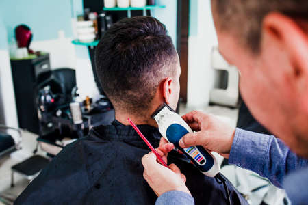 latin man stylist cutting hair to a client in a barber shop in Mexico
