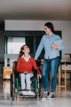 Young latin woman in wheelchair working with computer at workplace or office in Mexico cityの写真素材