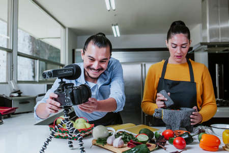 latin couple blogger vlogger and online influencer recording video content on mexican food in the kitchen in Mexico cityの写真素材