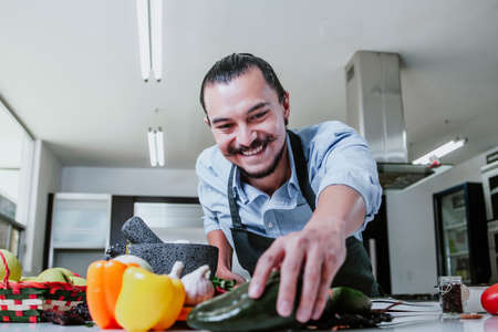 latin man cooking at home preparing salad or mexican sauce in kitchen at home in Mexico cityの写真素材