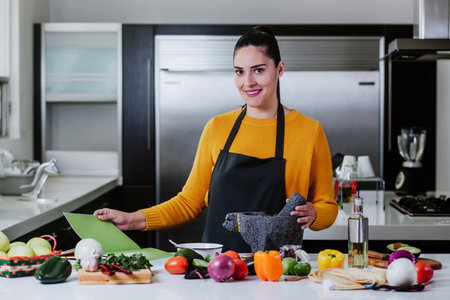 latin woman cooking mexican sauce food in kitchen at home in Mexico cityの写真素材