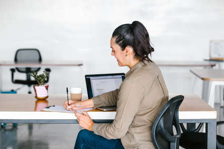 latin woman working with computer and headphones at the office or workplace in Mexico city