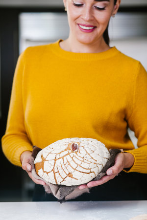 portrait of Latin Woman standing in kitchen holding Conchas traditional Mexican bread in Mexico cityの写真素材