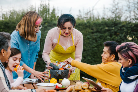 latin mother and daughter cooking mexican food at home, three generations of women in Mexicoの写真素材
