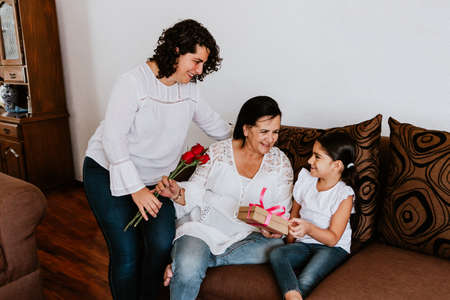 latin grandmother woman with daughter or grandchild celebrating birthday, 8 March International women holiday or Happy Mother's Day in Mexico cityの写真素材