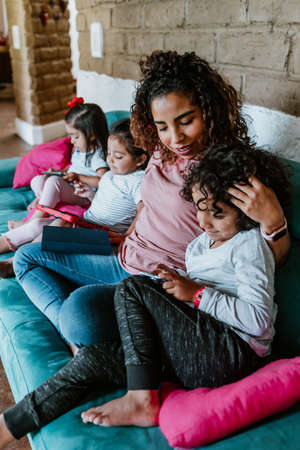 Young latin woman and her little children reading books at home in Mexico cityの写真素材