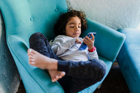 portrait of latin child holding a smartphone at home in Mexico city