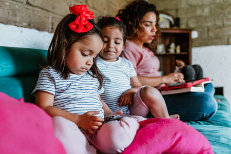 latin child or little girls with phone and tablet at home in Mexico cityの写真素材