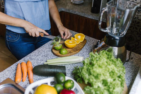 Latin Woman making green smoothie or Detox juice in kitchen at Home in healthy eating concept in...