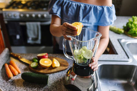 Latin Woman making green smoothie or Detox juice in kitchen at Home in healthy eating concept in Mexicoの写真素材