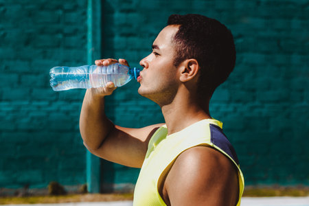 portrait of young latin man drinking a bottle of water after training in Mexico Latin Americaの写真素材