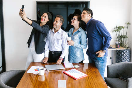 Latin business team taking selfies standing while working in office in Latin Americaの写真素材