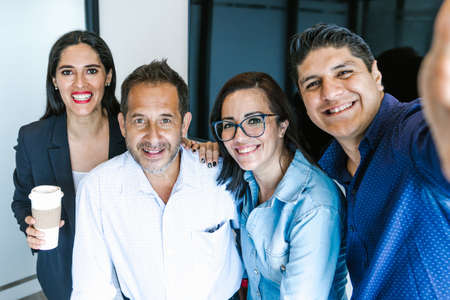 Smiling hispanic office colleagues taking selfie at meeting in conference room in Latin Americaの写真素材