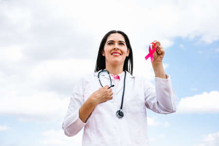 portrait of latin woman doctor holding pink breast cancer awareness ribbons in Mexico Latin Americaの写真素材