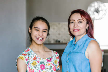 Hispanic teenage girl with cerebral palsy and her mother at home in Mexico City in disability...