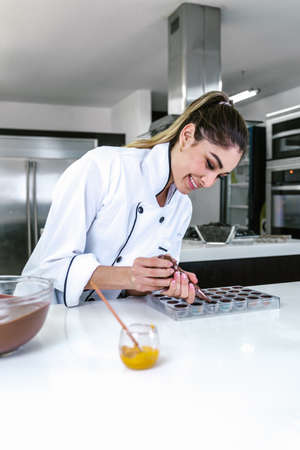 young latin woman chocolatier in chef hat with mexican chocolates candies on plate in a commercial kitchen in Mexico Latin Americaの写真素材